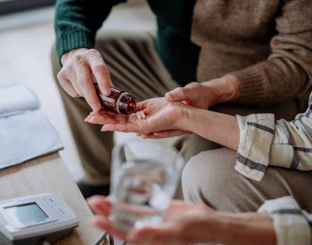 Close-up of senior man giving his wife medication at home