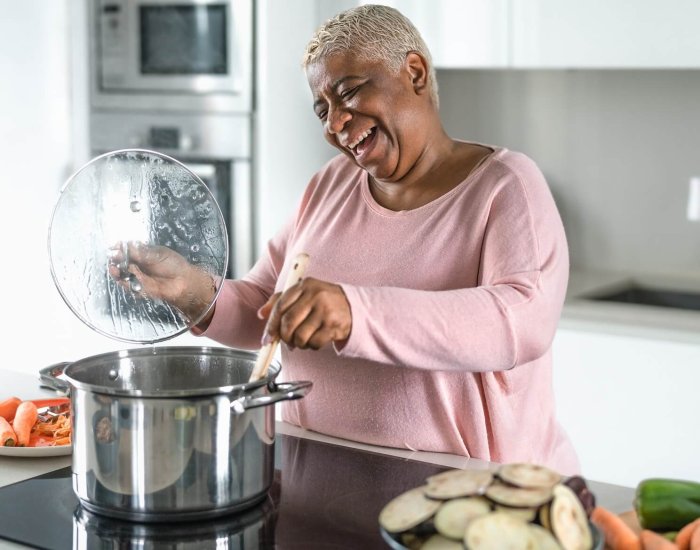Happy senior woman having fun preparing lunch in modern kitchen